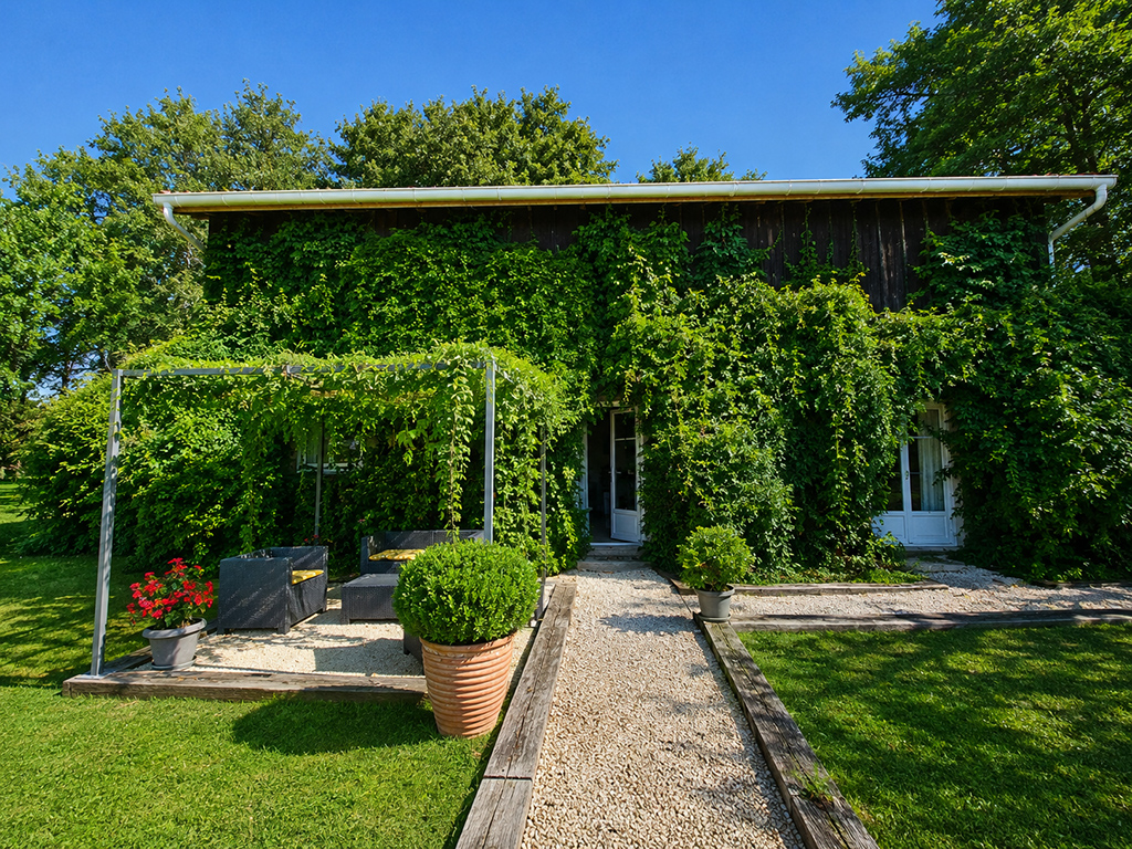 Façade végétalisée du Gîte Pigerot et allée menant à l’entrée.