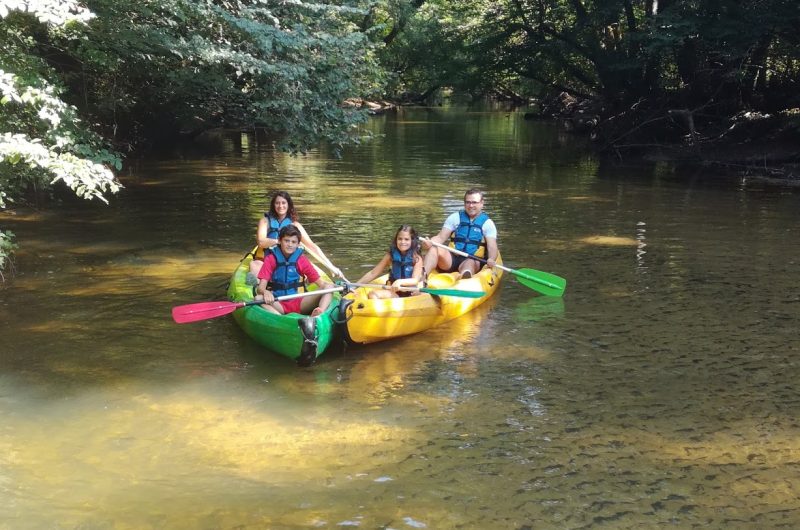 Famille en canoë-kayak sur une rivière bordée d’arbres à Roquefort, dans les Landes